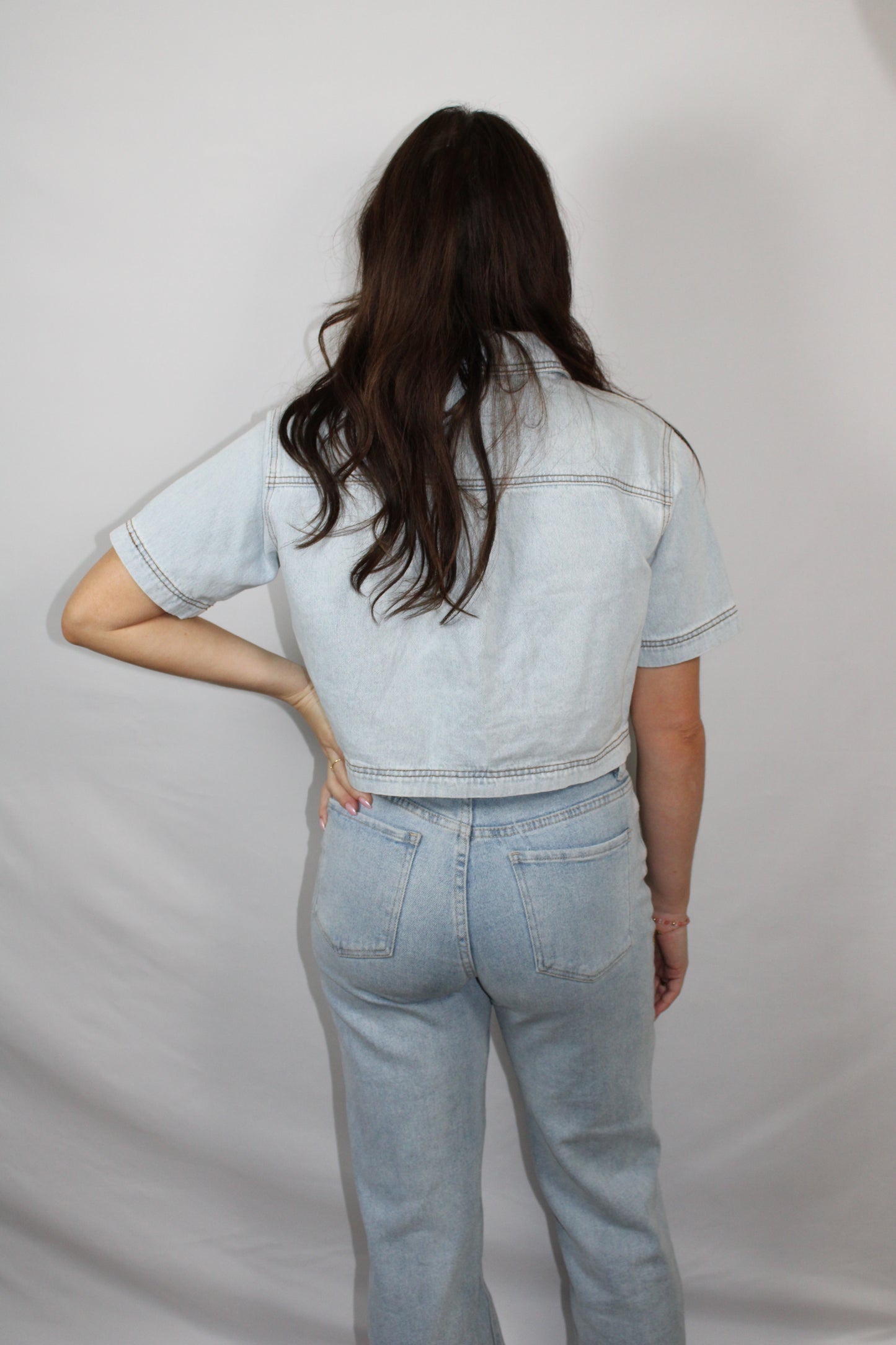 Achterzijde van de blauwe spijker top gedragen door een model op een jeans.