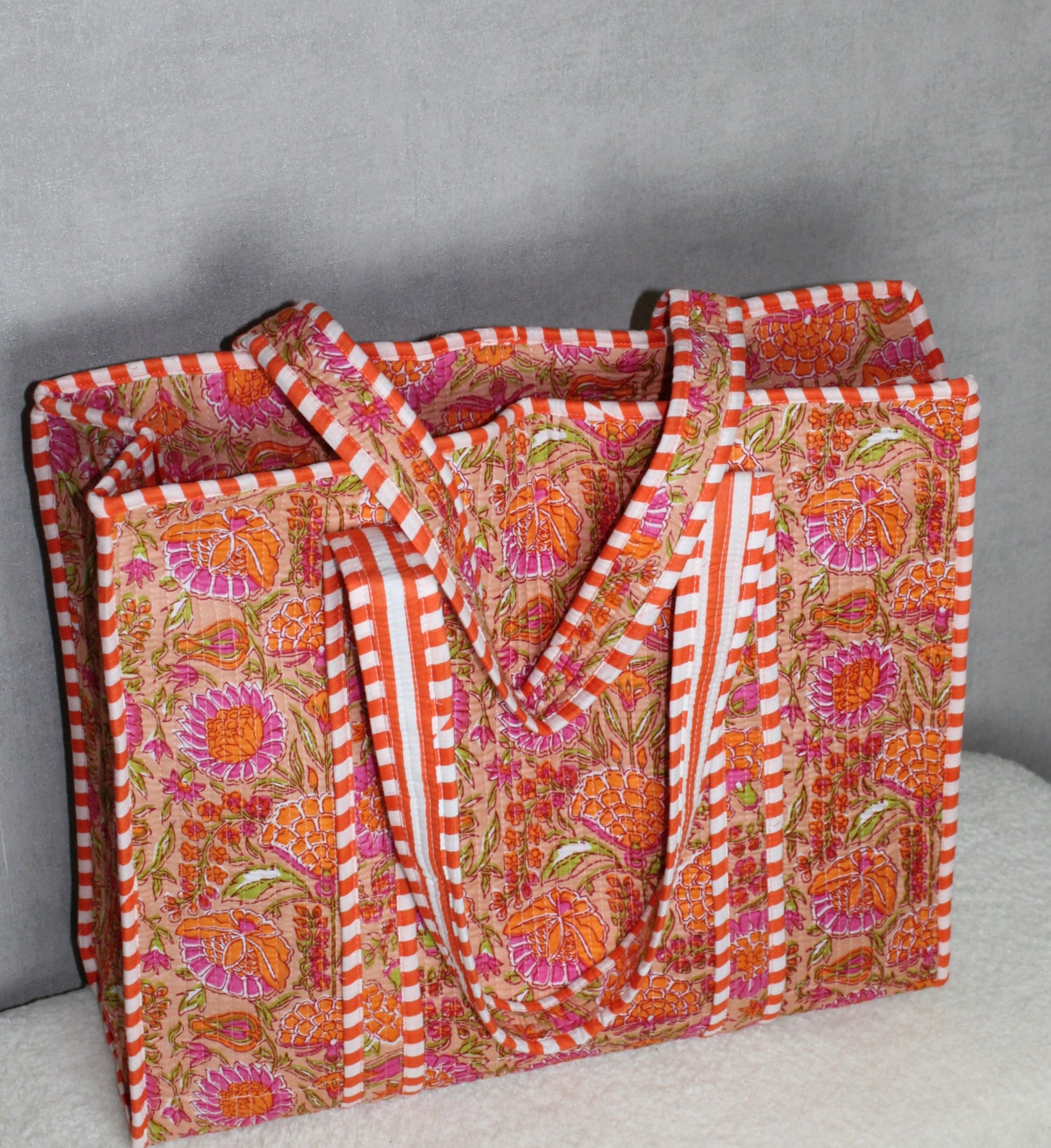 Zijaanzicht van de oranje gebloemde dames shopper om het ruime formaat en de schouderbanden te tonen.