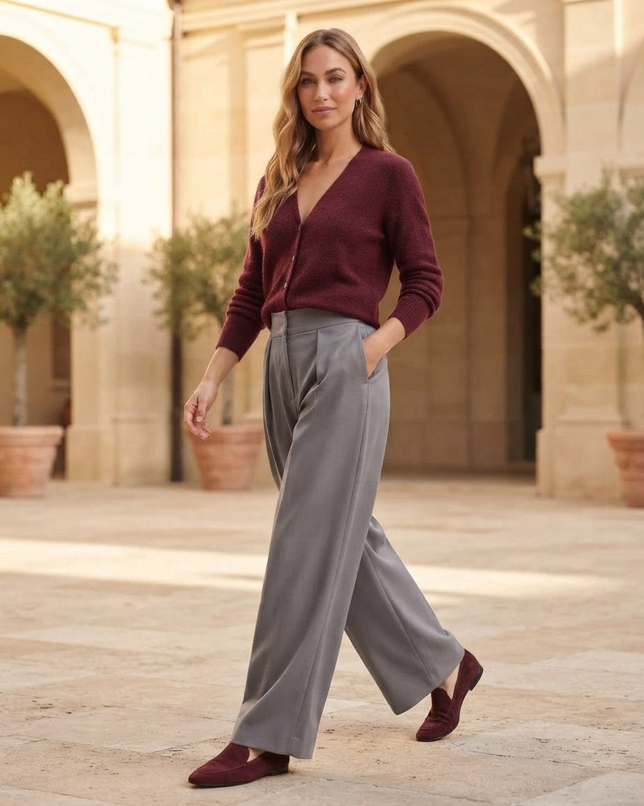 Grijze wide leg pantalon met plooien gecombineerd met een bordeaux baby alpaca cardigan in een luxe lifestyle setting