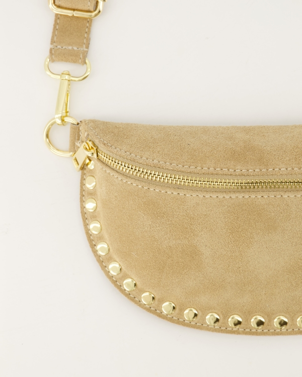 Zijaanzicht van beige suède half‑moon small bag met gold studs en verstelbare strap.