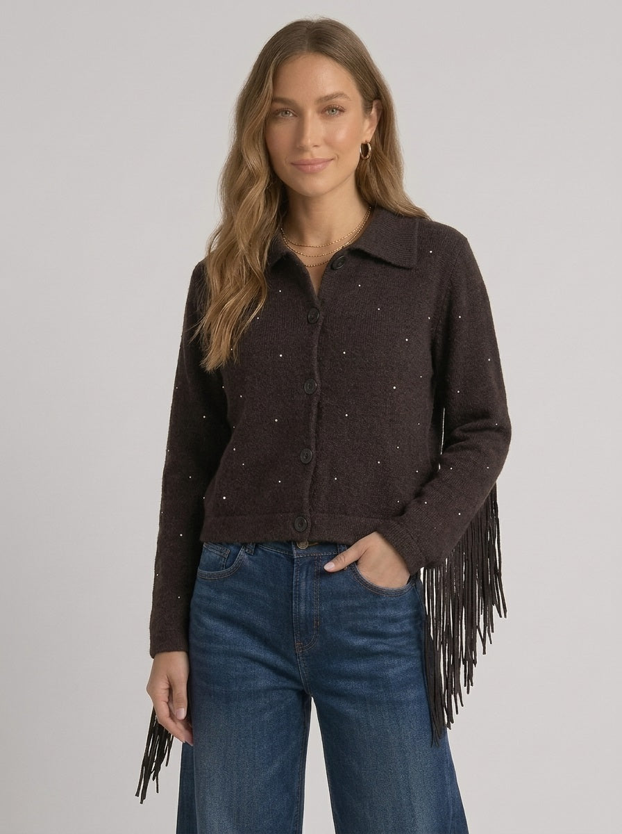 Model draagt de voorkant van het donkerbruine gebreide vest met subtiel glinsterende strass-steentjes, een polokraag en knopen, gecombineerd met een denim jeans.