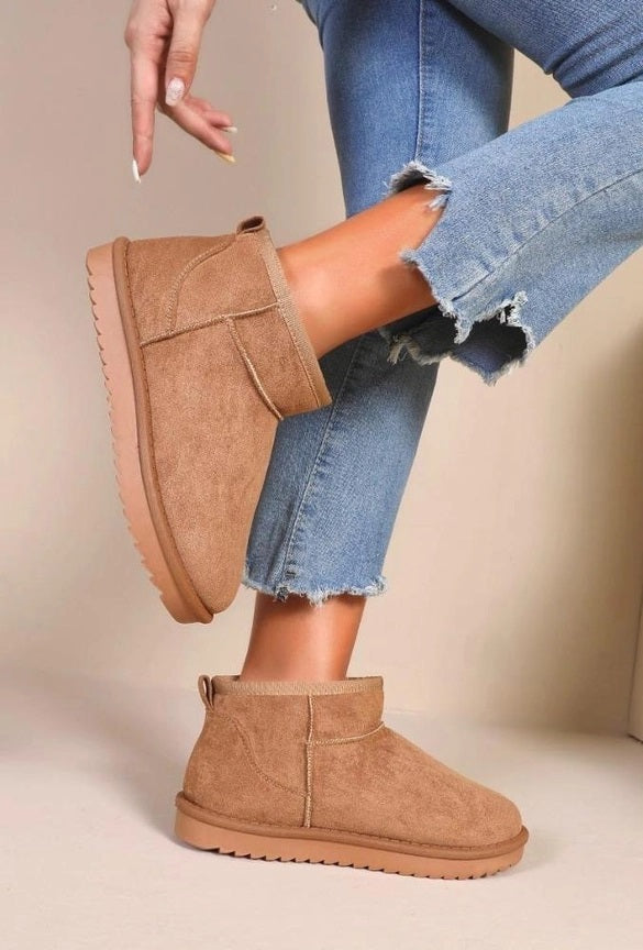 Model draagt de trendy camel faux suède mini winterlaarsjes onder een casual blauwe jeans.