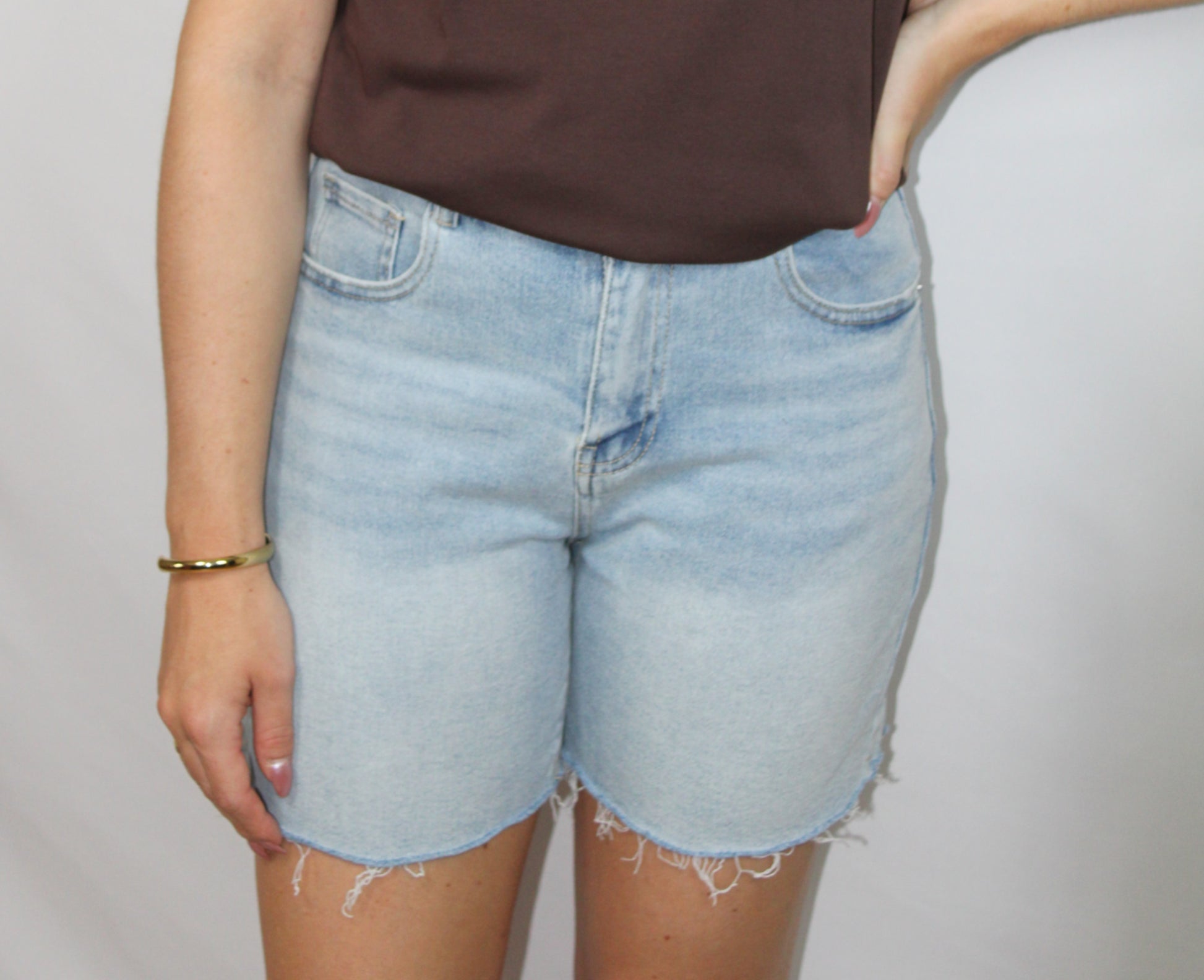 Lichtblauwe denim short voor dames met casual fit, stretch en gerafelde onderzijde op lichte studioachtergrond.