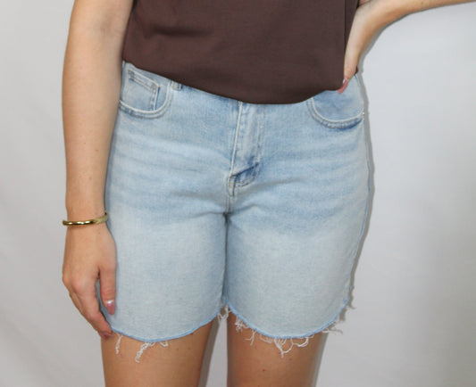 Lichtblauwe denim short voor dames met casual fit, stretch en gerafelde onderzijde op lichte studioachtergrond.