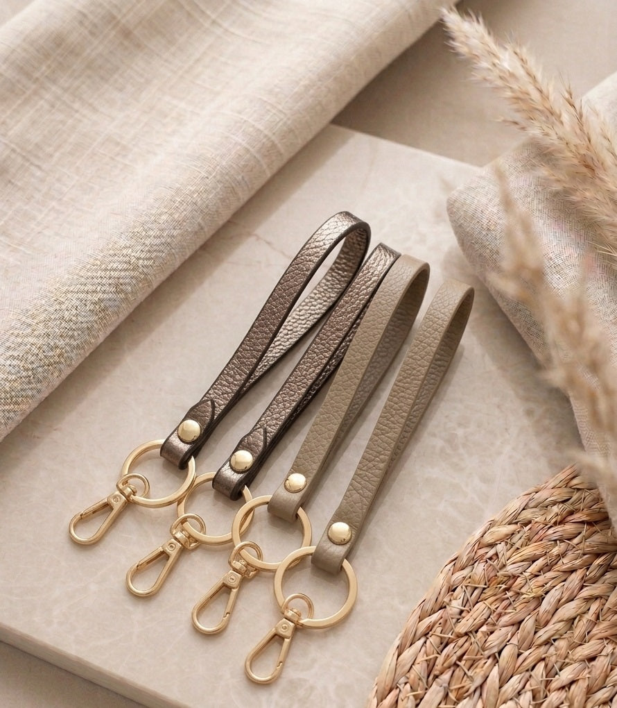 Gedetailleerde productfoto van het minimalistische design en de stevige lederen structuur van de taupe sleutelhanger Evi.