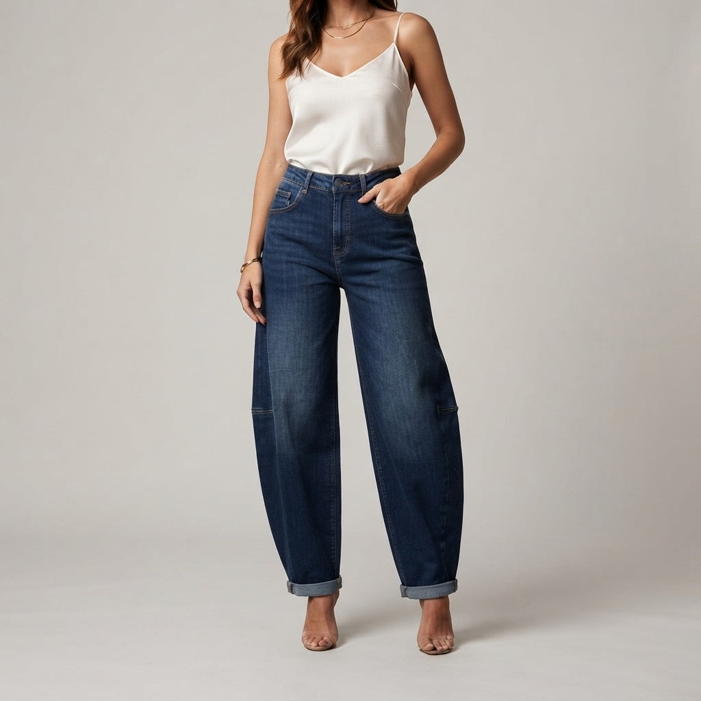 Model draagt een donkerblauwe high-waisted balloon jeans voor dames met wijde pijpen en een witte top