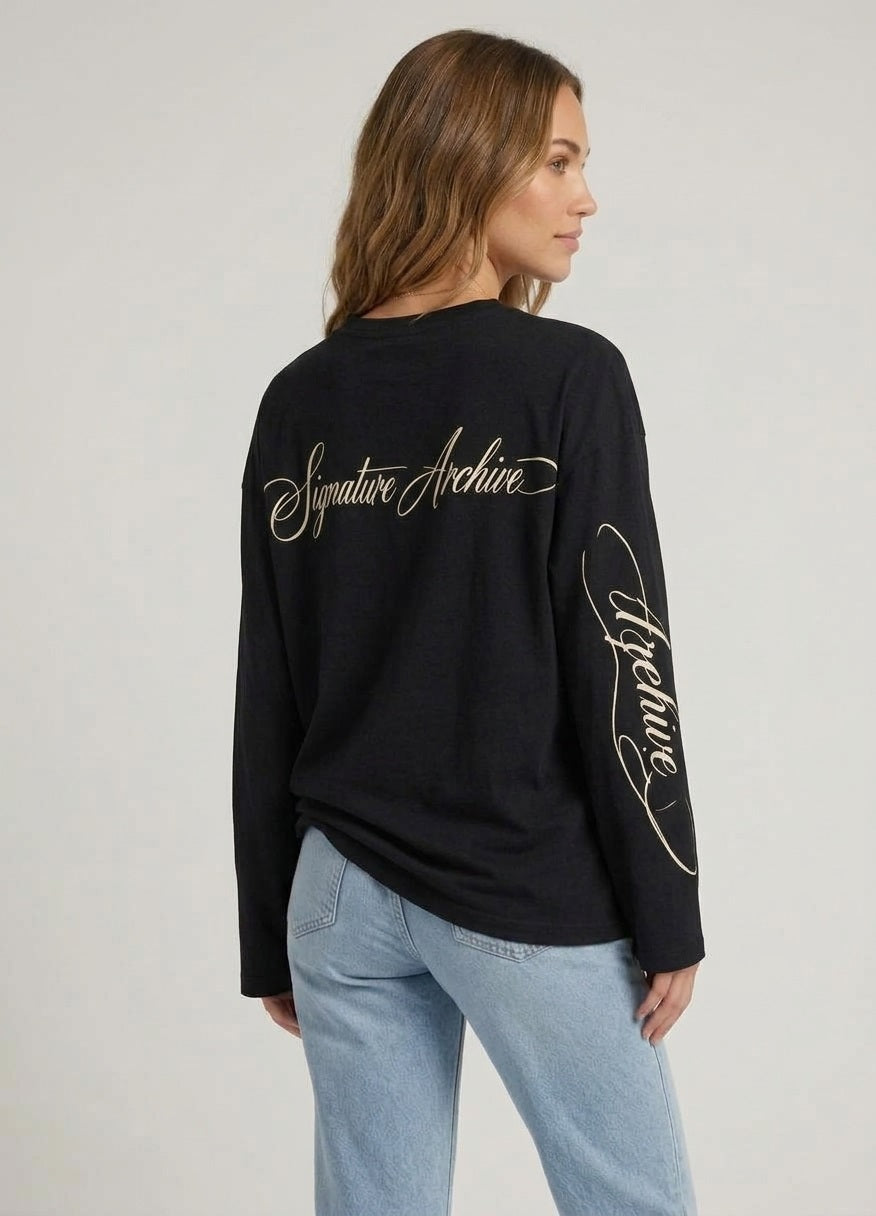 Achterkant van de zwarte dames longsleeve, tonend de grote, elegant gecursiveerde witte tekstopdruk Signature Archive op de rug en mouw.