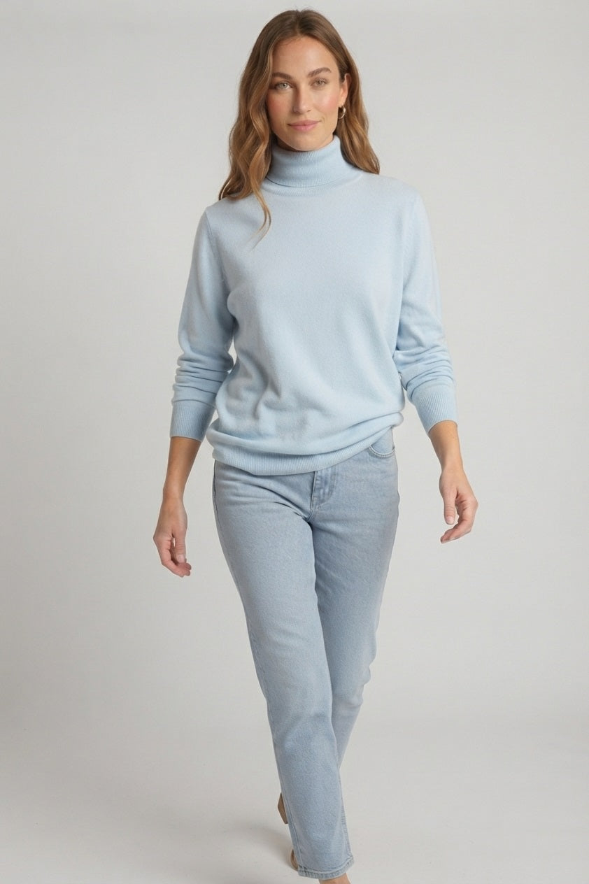Lopende model draagt een comfortabele lichtblauwe dames coltrui gecombineerd met een bijpassende denim jeans