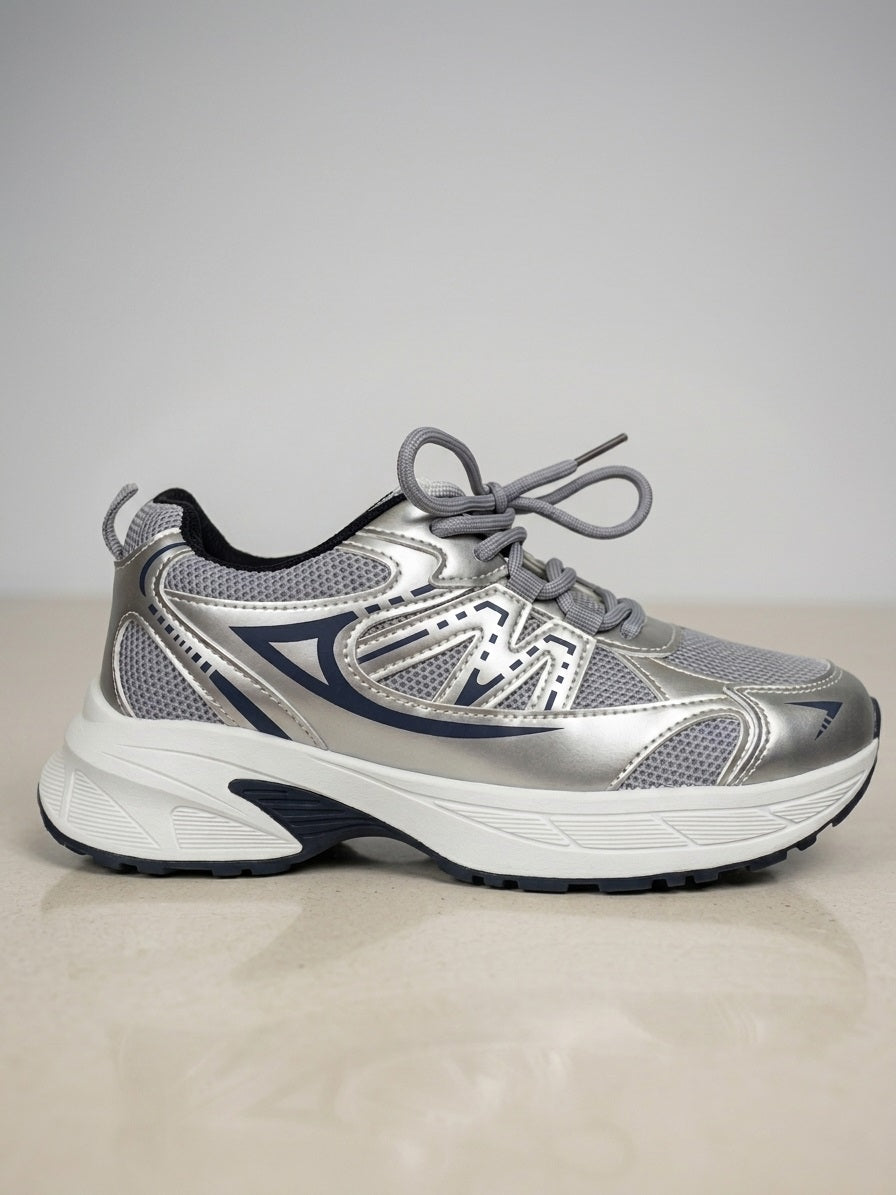 Zijaanzicht van zilveren sneaker met mesh panelen en metallic overlays.