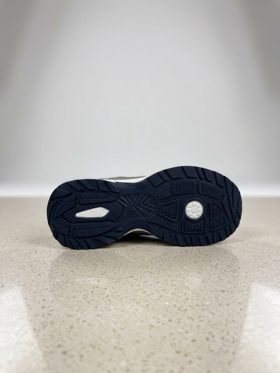 Close‑up van de zool van een zilveren sneaker met blauwe antislipstructuur.
