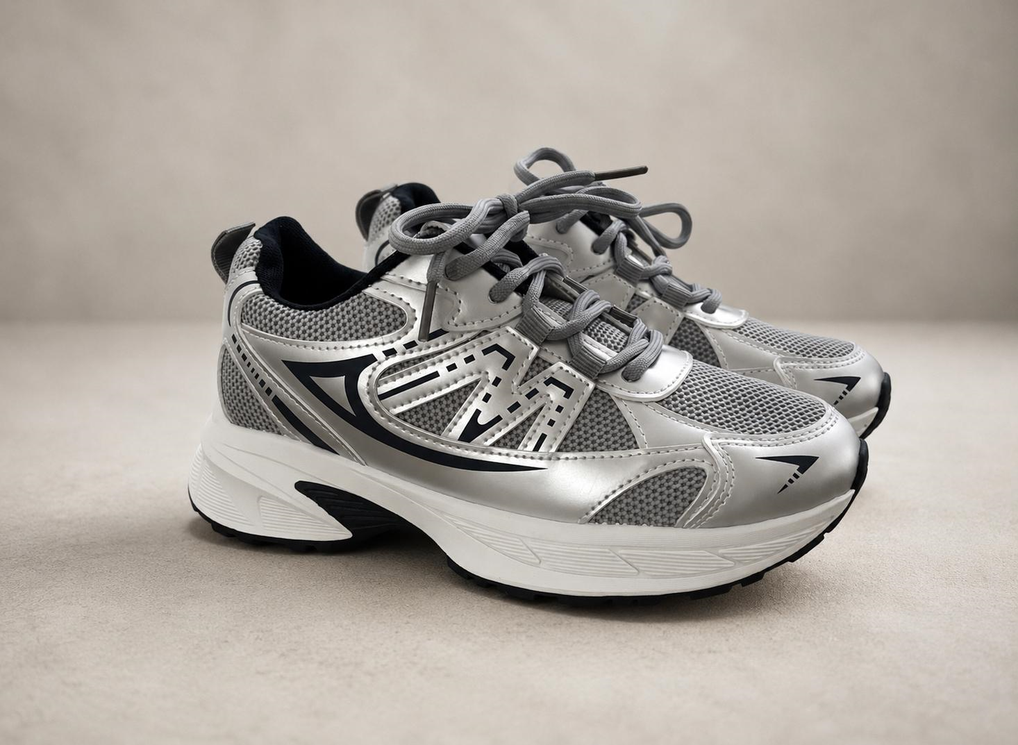 Silver navy athletic sneakers op neutrale studio‑achtergrond in zijaanzicht.