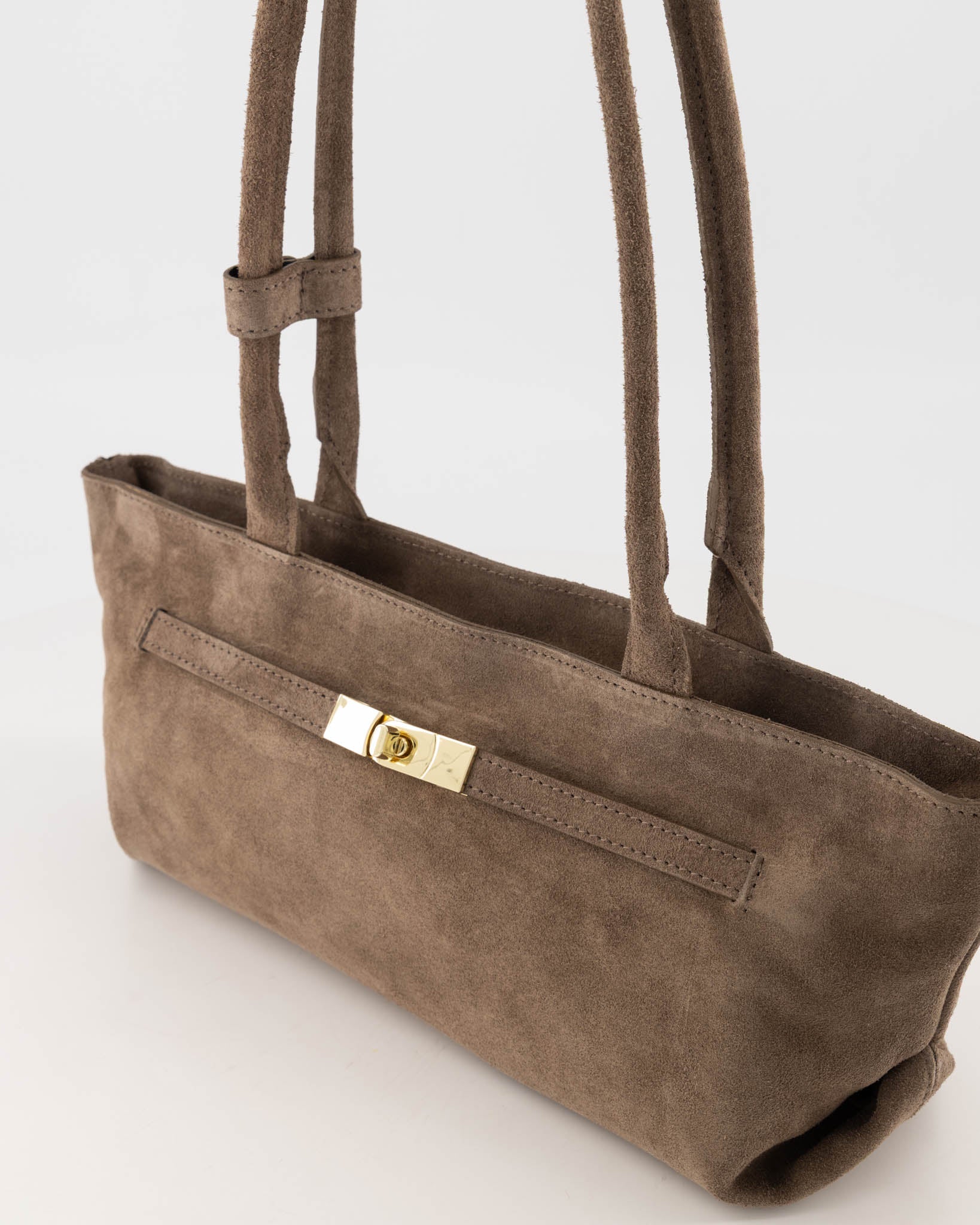 Detail van gold clasp op taupe suède shoulder bag met front‑strap.
