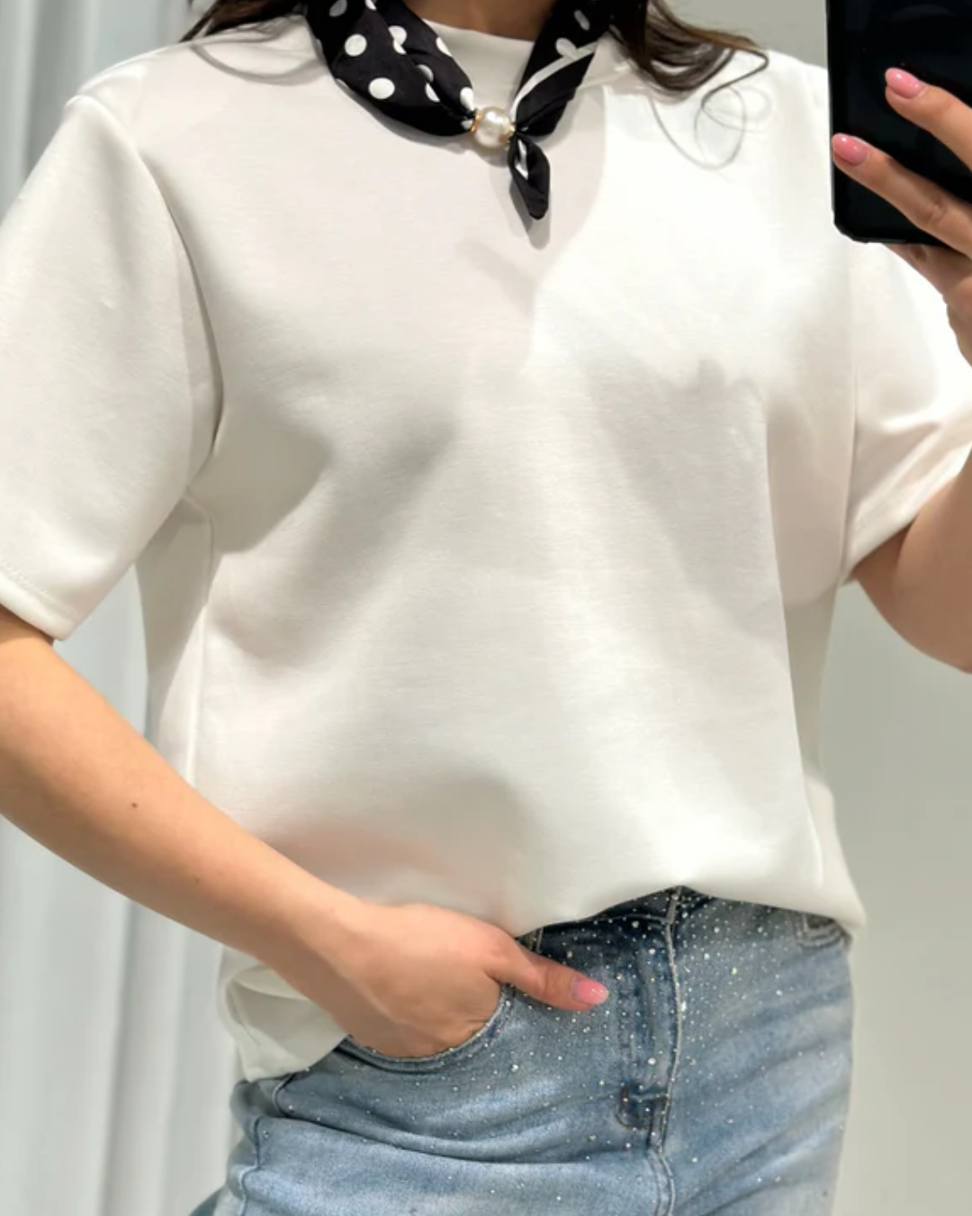 Zijaanzicht van het witte dames T-shirt met schoudervulling om de perfecte pasvorm te tonen.